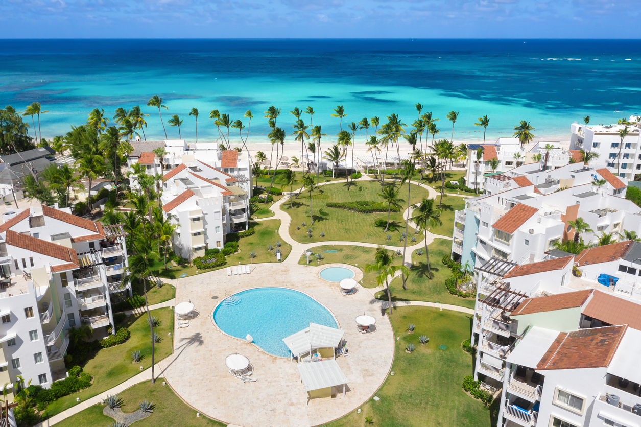Caribbean beach of Atlantic ocean with luxury resort, coconut palm trees and azure water. Travel destination for vacation. Aerial view from drone