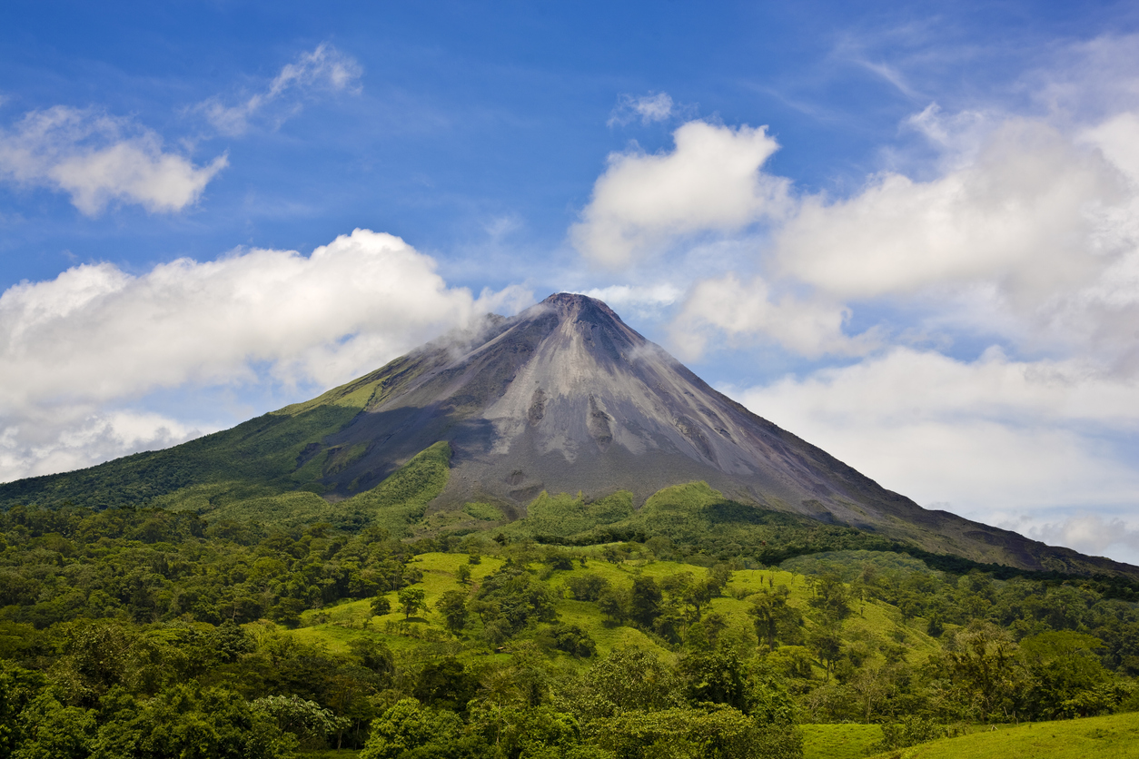 Volcano Arenal in Costa Rica on a partly cloudy day. Northeastern slopes. Arenal Volcano is an active andesitic (meaning that the rock has been crystallized from silicate minerals) stratovolcano in north-western Costa Rica, where Arenal is the youngest and most active of all the mountains. It was presumed extinct until July 29, 1968 when an earthquake caused it to erupt, after approximately 400 years of dormancy. Arenal rises 1657 m above sea level and overlooks Lake Arenal; both are part of Arenal Volcano National Park