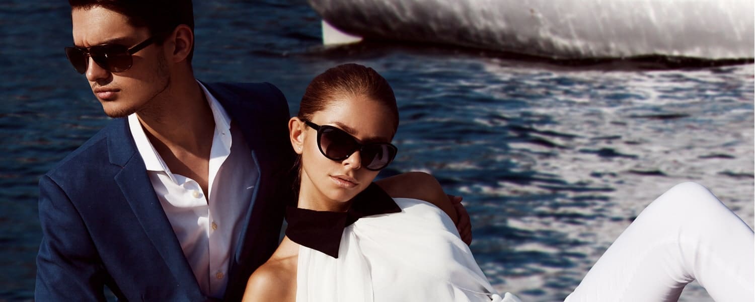 Young fashionable couple wearing sunglasses with water behind