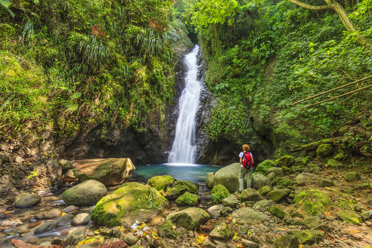 Au Coin Falls in Grenda, with a woman carrying a red backpack