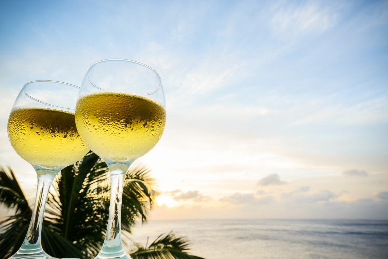 Sunset lights up two glasses of sparkling white wine on a balcony overlooking the Caribbean Sea on the island of Curacao.
